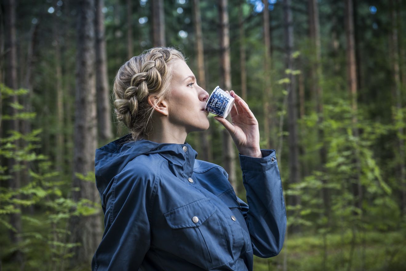 A woman drinking a Roberts Berrie cup in a Finnish pine forest